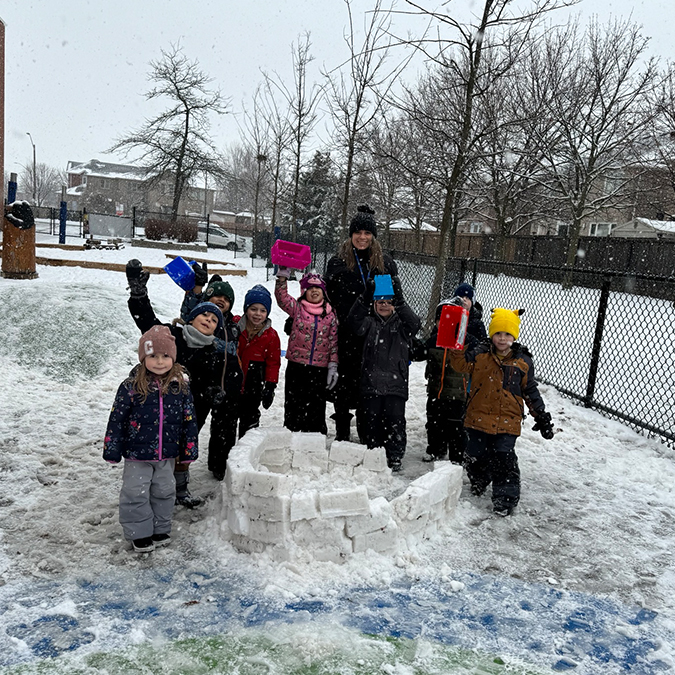 staff and children with snow fort